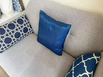 a blue pillow on a couch with two pillows at The Base Central Phuket in Phuket Town