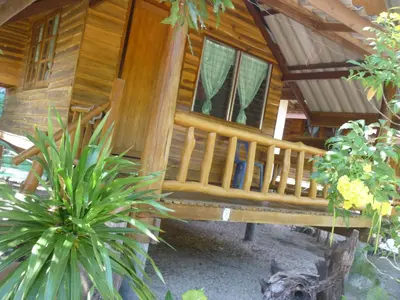a wooden cabin with a bench in a garden at Pasai Beach Lodge in Ko Yao Noi