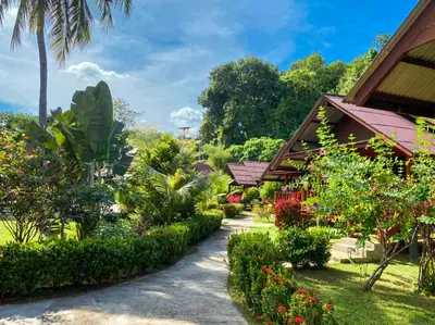 a path through a garden with flowers and trees at Koh Yao Seaview Bungalow in Ko Yao Noi