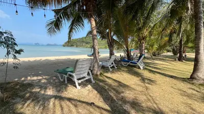 two chairs sitting on a beach with palm trees at Koh Yao Seaview Bungalow in Ko Yao Noi