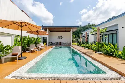 an infinity pool in a villa with chairs and umbrellas at Oasis by the Sea M1- House with Pool and Amenities in Phuket Town