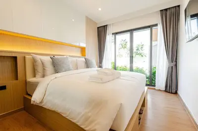 a bedroom with a large white bed with a window at Oasis by the Sea M2- House with Pool and Amenities in Phuket Town