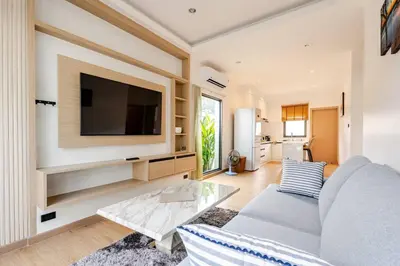 a living room with a couch and a tv on a wall at Oasis by the Sea M2- House with Pool and Amenities in Phuket Town