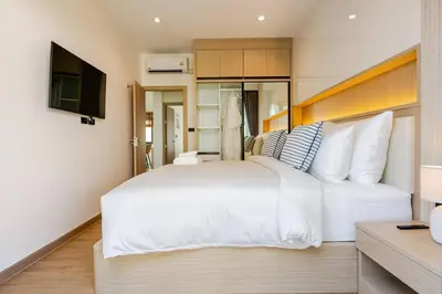 a bedroom with a large white bed and a television at Oasis by the Sea M3- House with Pool and Amenities in Phuket Town