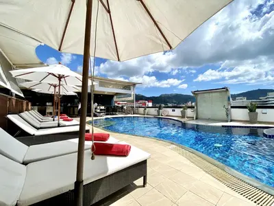 a swimming pool with two lounge chairs and an umbrella at Patong - Studio Condo - Absolute Bangla Unit in Patong Beach