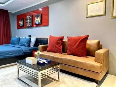 a living room with a brown couch and red pillows at Patong - Studio Condo - Absolute Bangla Unit in Patong Beach