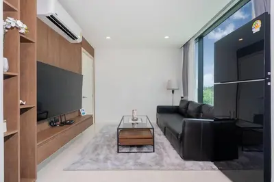 a living room with a black couch and a tv at Sunset Mountain View 2bedroom Patong in Patong Beach