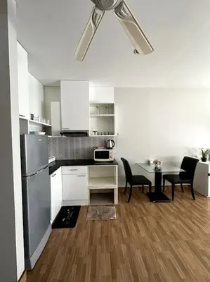 a white kitchen with a table and a refrigerator at Сhic condo студия с бассейном in Karon Beach