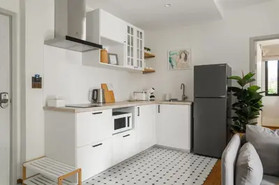 a kitchen with white cabinets and a black refrigerator at Title Halo Wild Spirit Naiyang Pool Gym 2BR in Nai Yang Beach