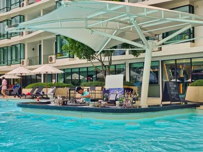 a poolside bar with an umbrella in the water at Family Luxe Apartment in 5 Star hotel in Phuket Town