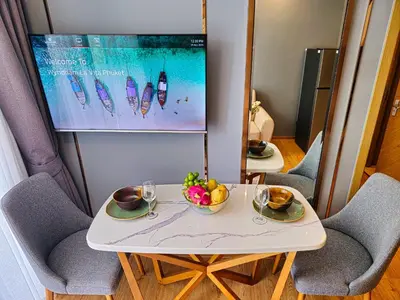 a table with two chairs and a bowl of fruit on it at Family Luxe Apartment in 5 Star hotel in Phuket Town