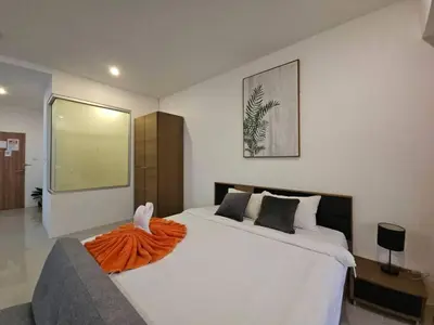 a bedroom with a large bed with an orange blanket on it at Chic condominium karon beach in Karon Beach