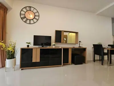a living room with a tv and a clock on the wall at Chic condominium karon beach in Karon Beach