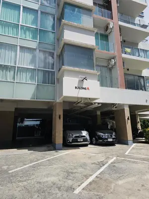 a building with two cars parked in a parking lot at Chic condominium karon beach in Karon Beach