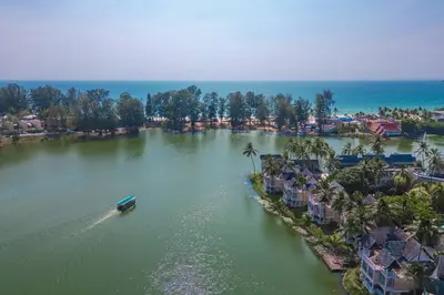 an aerial view of a resort with a boat in the water at Angsana Laguna Phuket, family suite villa duplex, private unit with hotel kids club, pools and beach access in Laguna Phuket