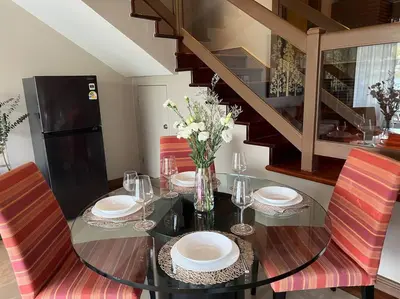 a dining room table with plates and flowers on it at Angsana Laguna Phuket, family suite villa duplex, private unit with hotel kids club, pools and beach access in Laguna Phuket