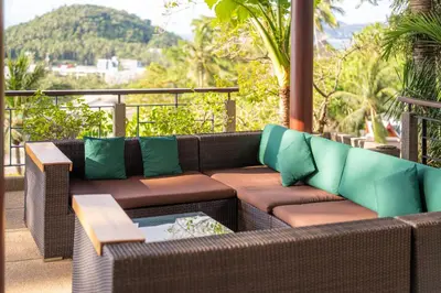 a brown couch with green pillows on a balcony at surin Luxurious 6br private swimming pool stunning sunset in Phuket Town