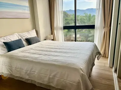 a bedroom with a white bed with a large window at Cozy apartment with a Resort Facilities in Bangtao in Bang Tao Beach
