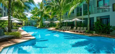 a swimming pool in front of a building with palm trees at Cozy apartment with a Resort Facilities in Bangtao in Bang Tao Beach