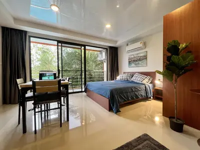 a bedroom with a bed and a table and a desk at Mai Khao Serenity in Ban Mai Salae