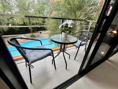 a balcony with a table and chairs and a pool at Mai Khao Serenity in Ban Mai Salae
