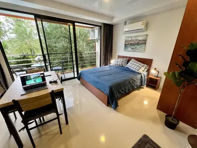 a bedroom with a bed and a desk with a laptop at Mai Khao Serenity in Ban Mai Salae