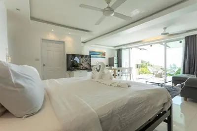 a bedroom with a large white bed and a living room at 4 Big Separate Apartments SeaView 8KingBeds v104 in Karon Beach