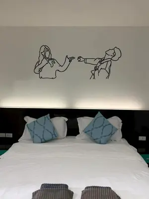 a bedroom with a bed with two people on the wall at sun flower \u4e00\u5367\u7cbe\u54c1\u5927\u5e8a\u623f in Patong Beach