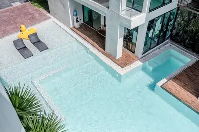a swimming pool in front of a house at Beach, Relax & Fun! VV Patong 2BR Apartment C201 just 5 min drive from Patong Nightlife in Patong Beach