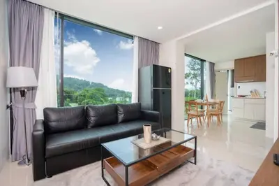 a living room with a black leather couch and a table at Beach, Relax & Fun! VV Patong 2BR Apartment C201 just 5 min drive from Patong Nightlife in Patong Beach