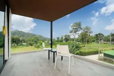 a balcony with two white chairs and a large window at Beach, Relax & Fun! VV Patong 2BR Apartment C201 just 5 min drive from Patong Nightlife in Patong Beach