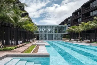 a swimming pool in front of a building with palm trees at Saturdays by Lotus Heart in Ban Saiyuan (1)