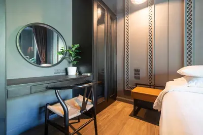 a bedroom with a mirror and a chair next to a bed at Saturdays by Lotus Heart in Ban Saiyuan (1)