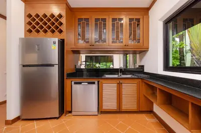 a kitchen with a stainless steel refrigerator and wooden cabinets at Meraya Villa with Private Pool Near Nai Harn Beach in Rawai Beach