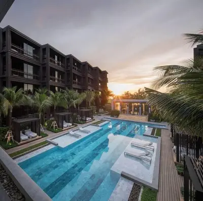 a large swimming pool with lounge chairs in front of a building at Saturdays Residence 1 bedroom Rawai in Ban Saiyuan (1)