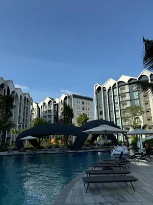 a pool with chairs and umbrellas in front of some buildings at The Title Halo1 2BD by MILL in Phuket