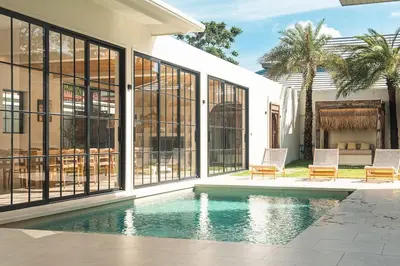 a swimming pool with two chairs and a house at Villa Cabana in Ban Saiyuan (1)