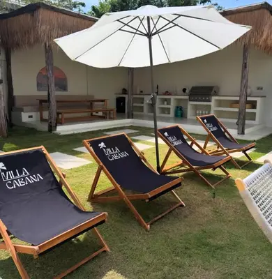 two lawn chairs and an umbrella in a yard at Villa Cabana in Ban Saiyuan (1)