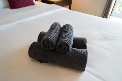 a pile of towels sitting on top of a bed at Tri's Miracle Apartment Kata in Kata Beach