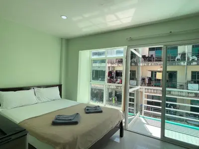 a bedroom with a bed and a large window at SHERRY'S Guest House in Patong Beach