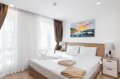 a bedroom with a large white bed with a window at Calypso condo in Rawai Beach