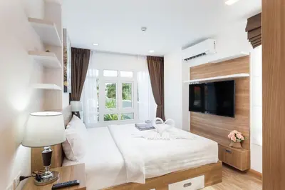 a bedroom with a large white bed and a tv at Calypso condo in Rawai Beach