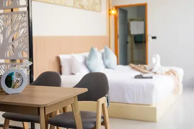 a bedroom with a bed and a table and chairs at Best Time Pool Suites in Chalong
