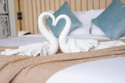 two white swans making a heart on a bed at Best Time Pool Suites in Chalong
