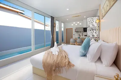 a bedroom with a large white bed with pillows at Best Time Pool Suites in Chalong