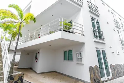 a white building with a balcony and a palm tree at Apartment Kata Ocean View in Kata Beach