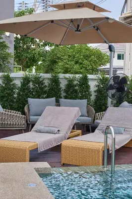 two beds and an umbrella next to a swimming pool at Phuket Paradise Retreat in Phuket Town