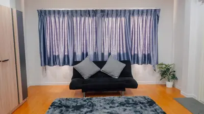 a living room with a black couch and a window at P&I Group Nana apartments 2&3 in Karon Beach