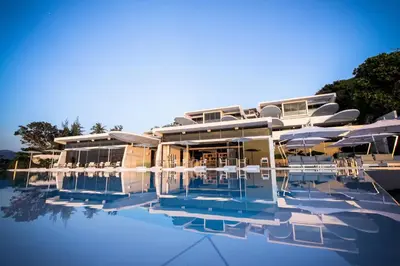 a resort with a pool with chairs and a building at Kata Rocks in Kata Beach