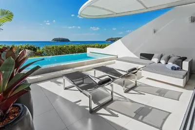 a patio with a pool and chairs and a table at Kata Rocks in Kata Beach